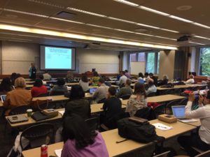 Dr. Susan Conrad presenting in front of a large group of symposium attendees