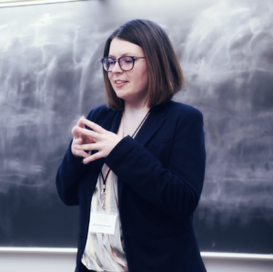 Aleksandra Swatek wearing professional clothing while speaking in front of a blackboard