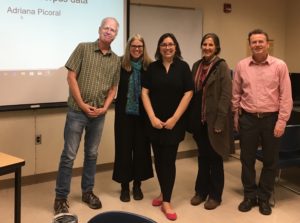 Dr. Adriana Picoral and her committtee stand in front of a large projector