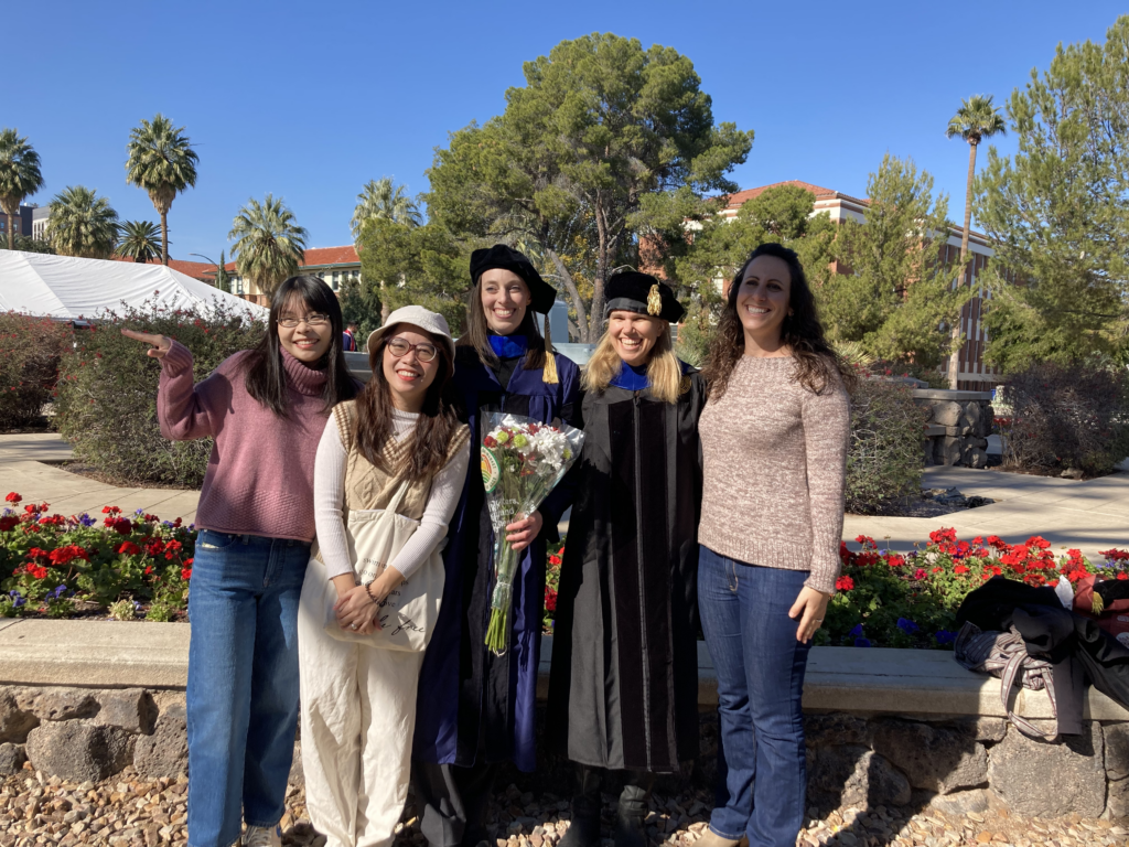Nina Conrad adorns graduation attire in a celebratory photo with fellow Crow team members.
