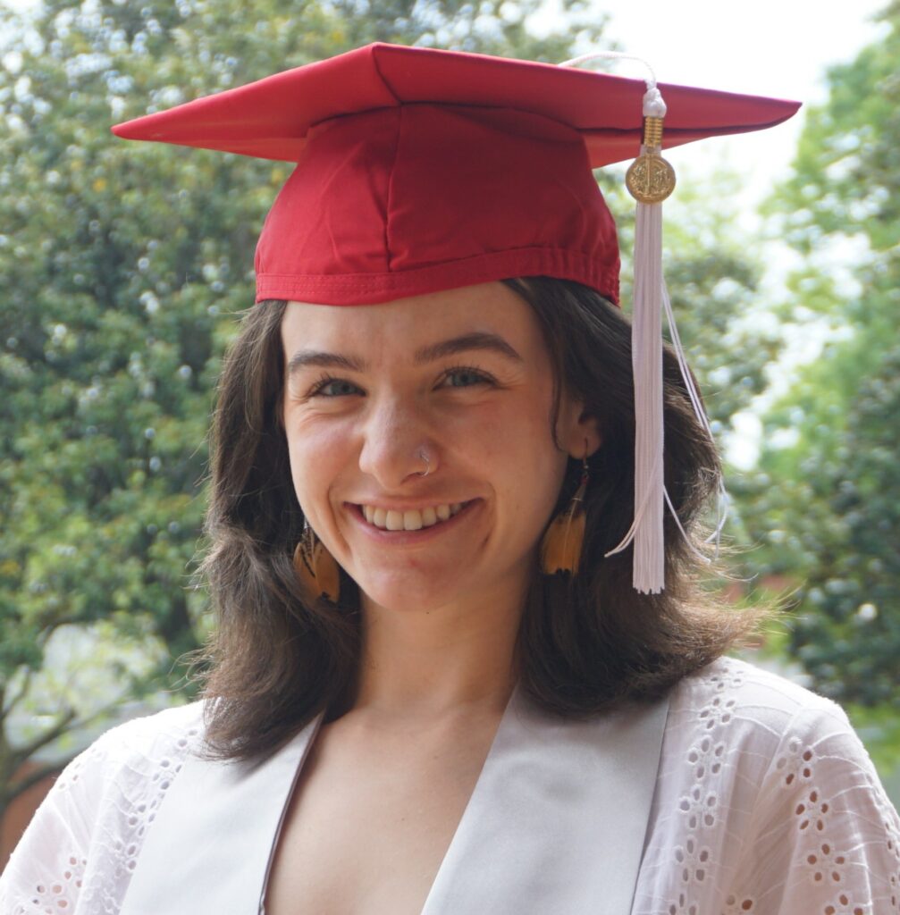 Alexis Jacobs wearing a red graduation cap with a white dress.