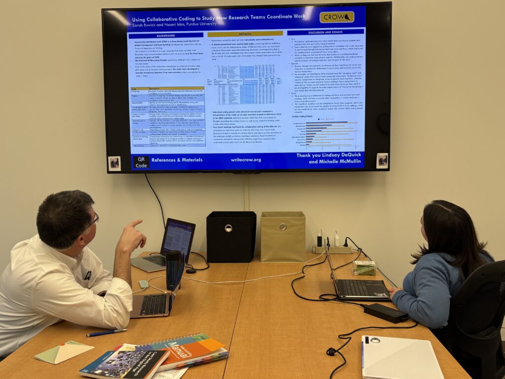 Dr. Bradley Dilger and Naomi Islas are in the new lab, sitting at the same large table as above, to go over some data on the TV screen, bolted to the wall in front of them. 